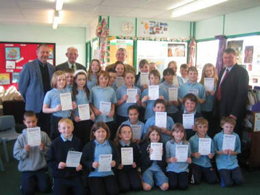 The photograph shows the children displaying their certificates with (l-r) Alan Doyle, Headteacher, Ted Clark, Chair of governors at the school, Dr Francis and Cllr John Rogers